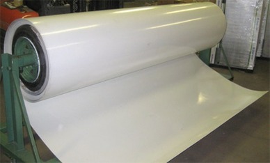 Metal Orders Large roll of white plastic sheeting on a machine, partially unrolled.